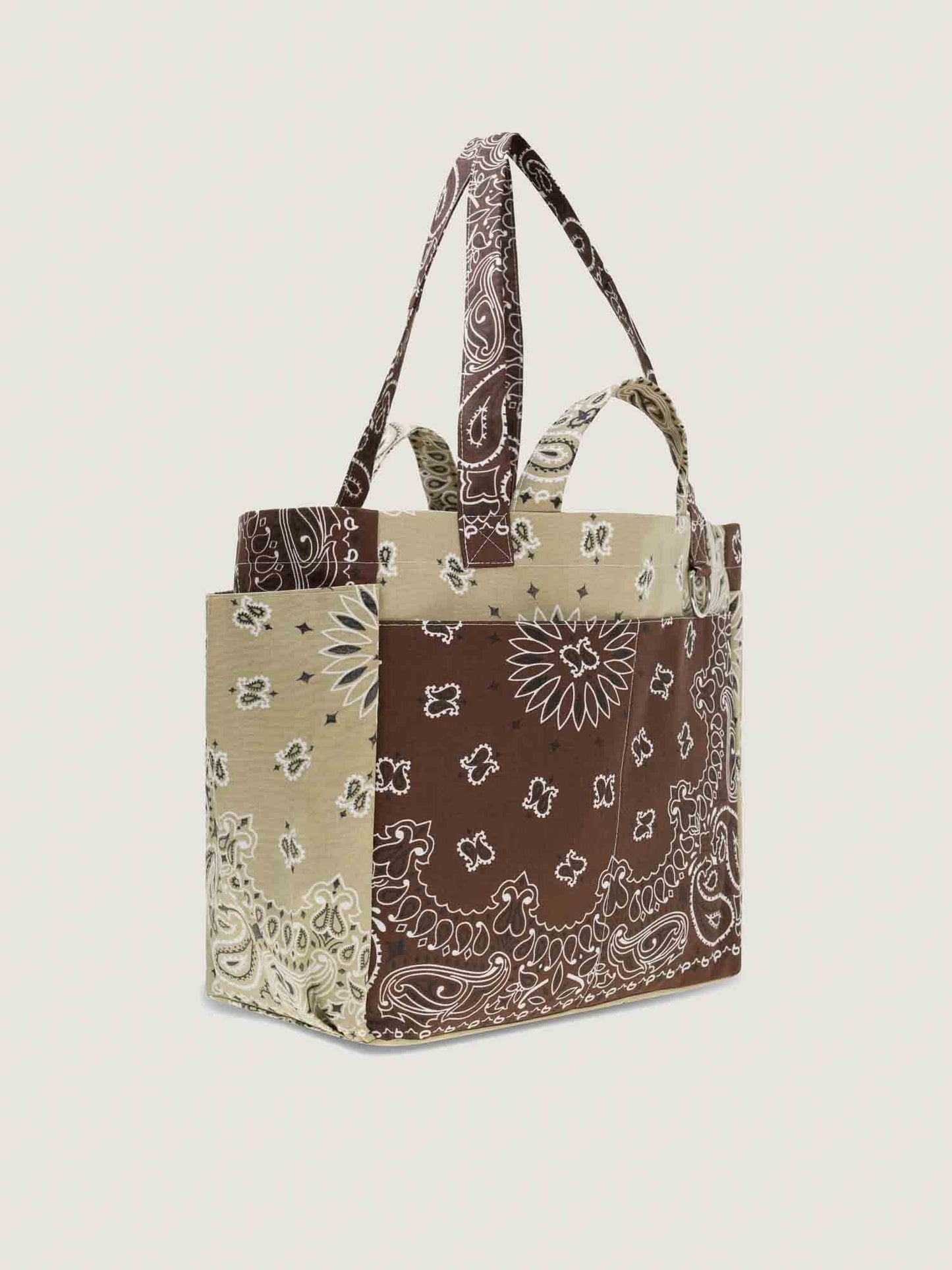 Tote bag with brown bandana pattern on a beige background, with inside and outside pockets, 2 handles and 2 shoulder straps, from brand Call it by your name, side view