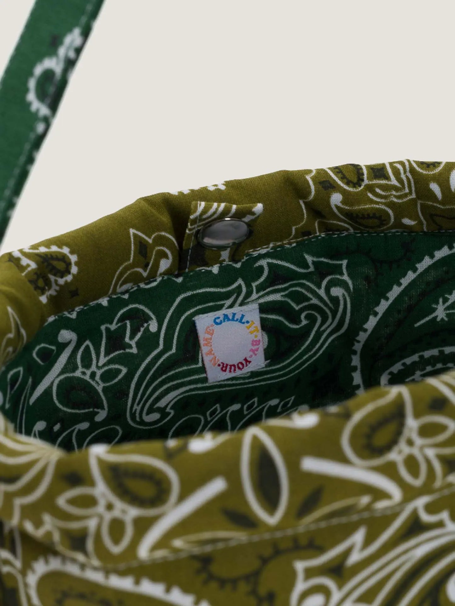 Green bandana bucket bag with adjustable strap by brand Call it by your name, close-up on tag