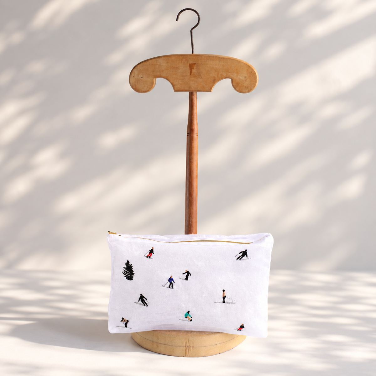 Brigitte Tanaka Skiers pouch in transparent white organza with tiny embroidered skiers, on a wooden stand