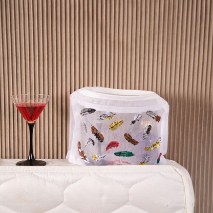 Brigitte Tanaka Feather pouch on a bedside table next to a glass of red wine