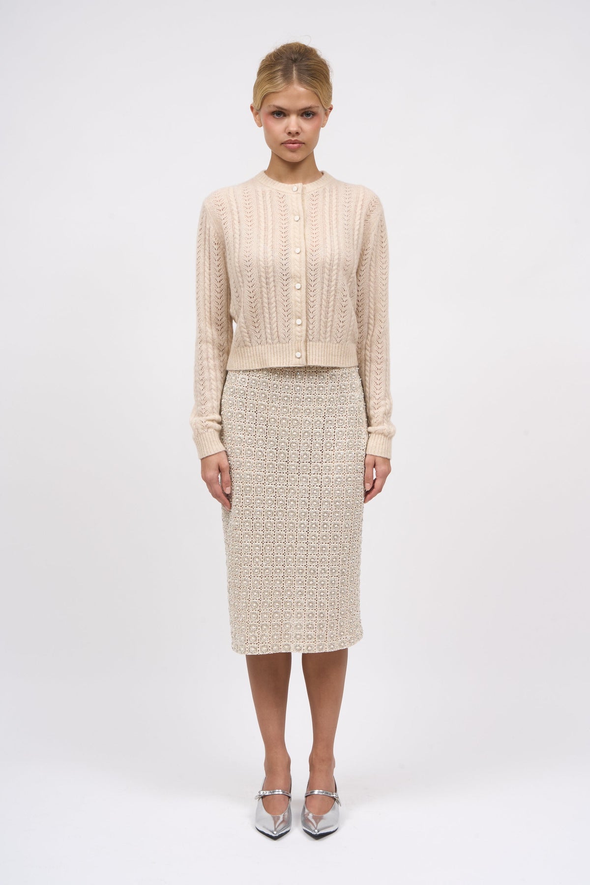 Paul & Joe Diamant guipure lace pencil skirt styled with a cream knit cardigan and silver heels, full-length front view