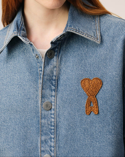 Blue denim shirt with a brown heart-shaped patch on a neutral background