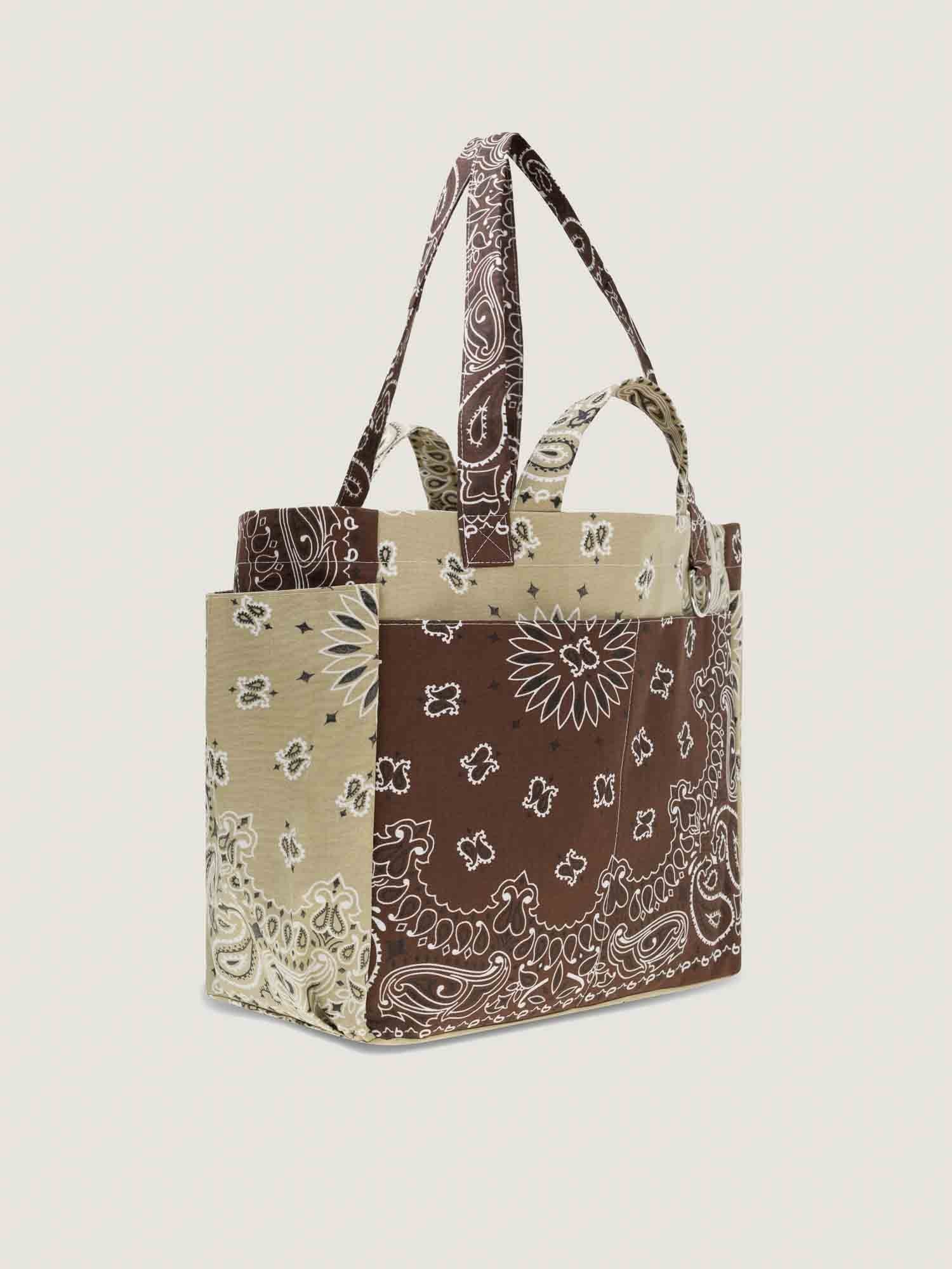 Tote bag with brown bandana pattern on a beige background, with inside and outside pockets, 2 handles and 2 shoulder straps, from brand Call it by your name, side view