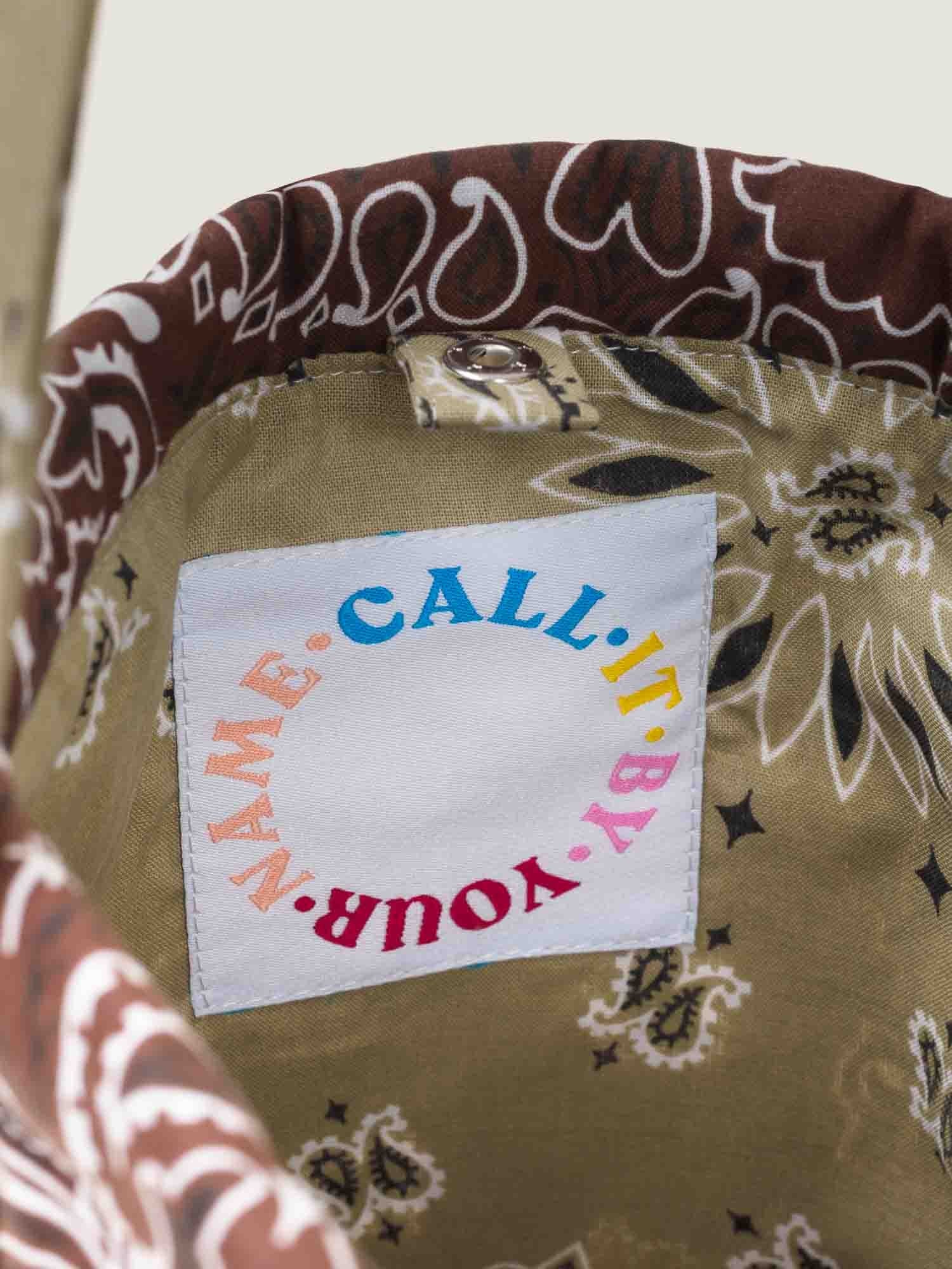 Brown and beige bandana bucket bag with adjustable strap, by brand Call it by your name, tag close-up
