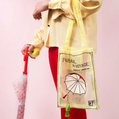 Model carrying the Brigitte Tanaka Parasol Voyage yellow tote with a pink umbrella