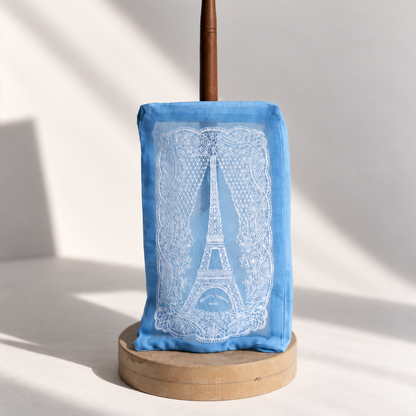 Brigitte Tanaka Eiffel Tower lace pouch in blue organza with white lace embroidery, on a wooden stand