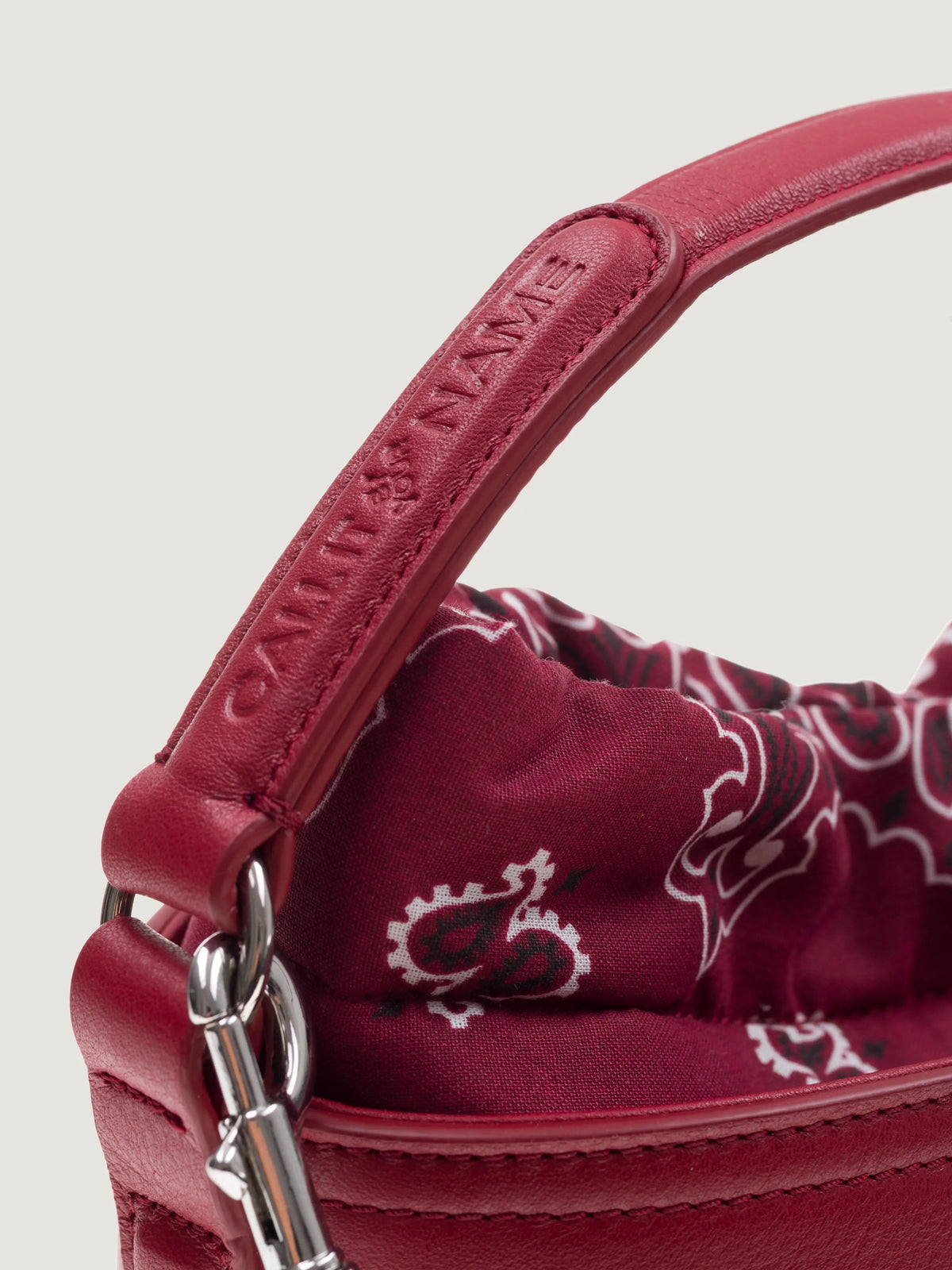 Close-up of the cherry leather handle and snap hook on the Call It By Your Name mini Peekaboo bag