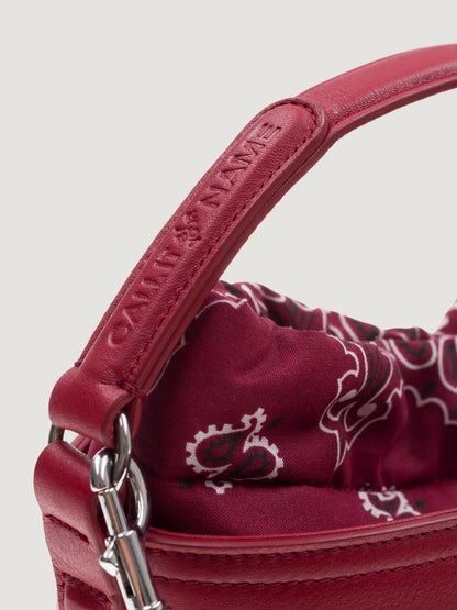 Close-up of the cherry leather handle and snap hook on the Call It By Your Name mini Peekaboo bag