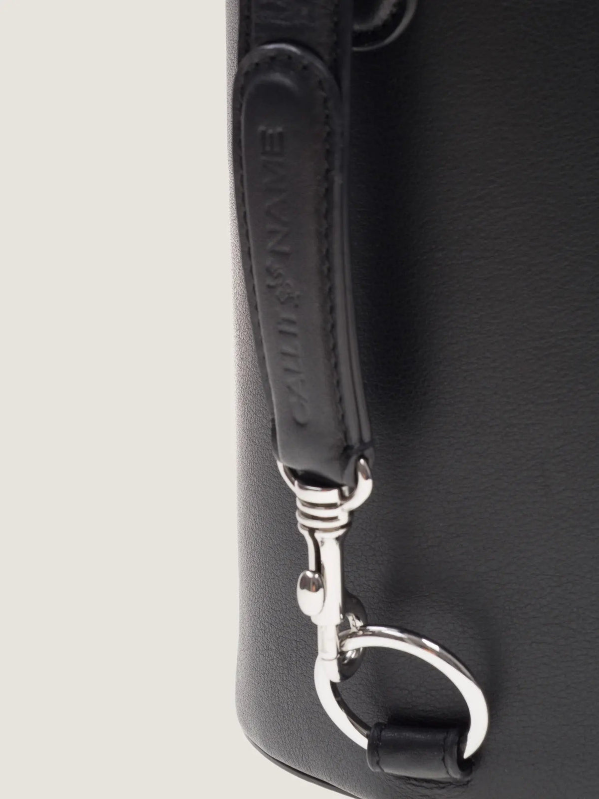 Close-up of the black leather strap and silver snap hook on the Call It By Your Name Peekaboo bag