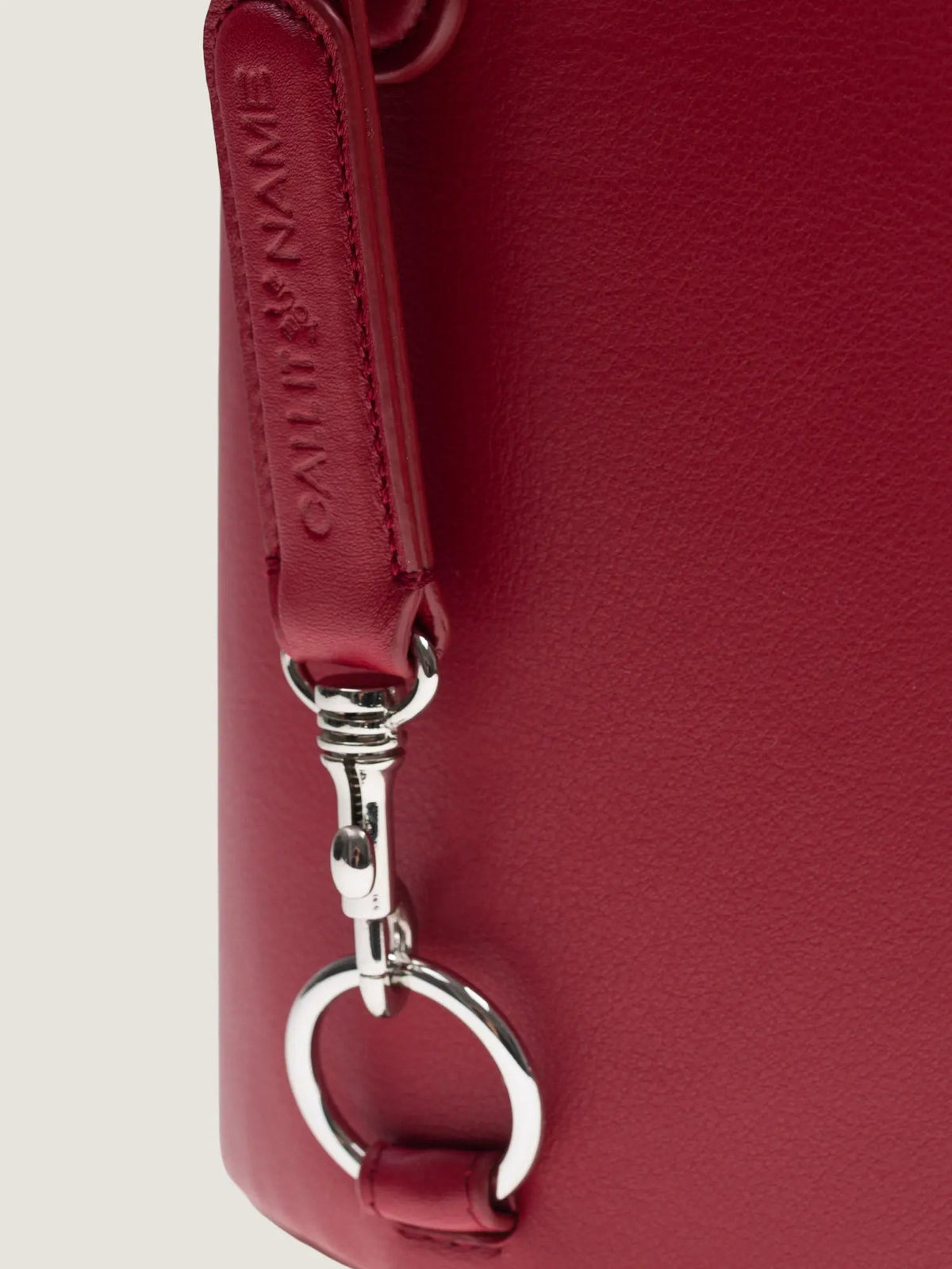 Close-up of the cherry leather strap and silver snap hook on the Call It By Your Name Peekaboo bag