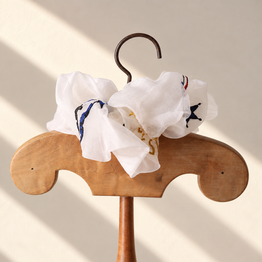 Brigitte Tanaka x Moulin Rouge Divination scrunchie in white organza with tarot card embroidery, on a wooden hanger