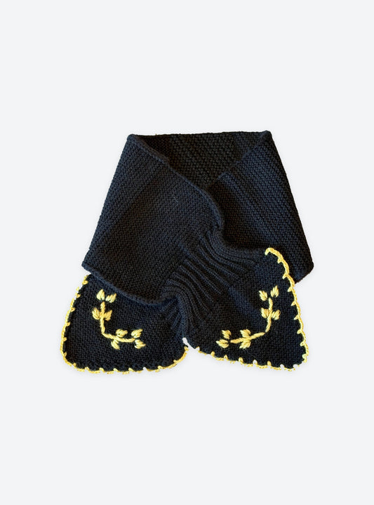 Flat-lay view of the Molli Dolce2 hand-embroidered neck scarf in deep black with gold leaf embroidery and scalloped blanket-stitch edging